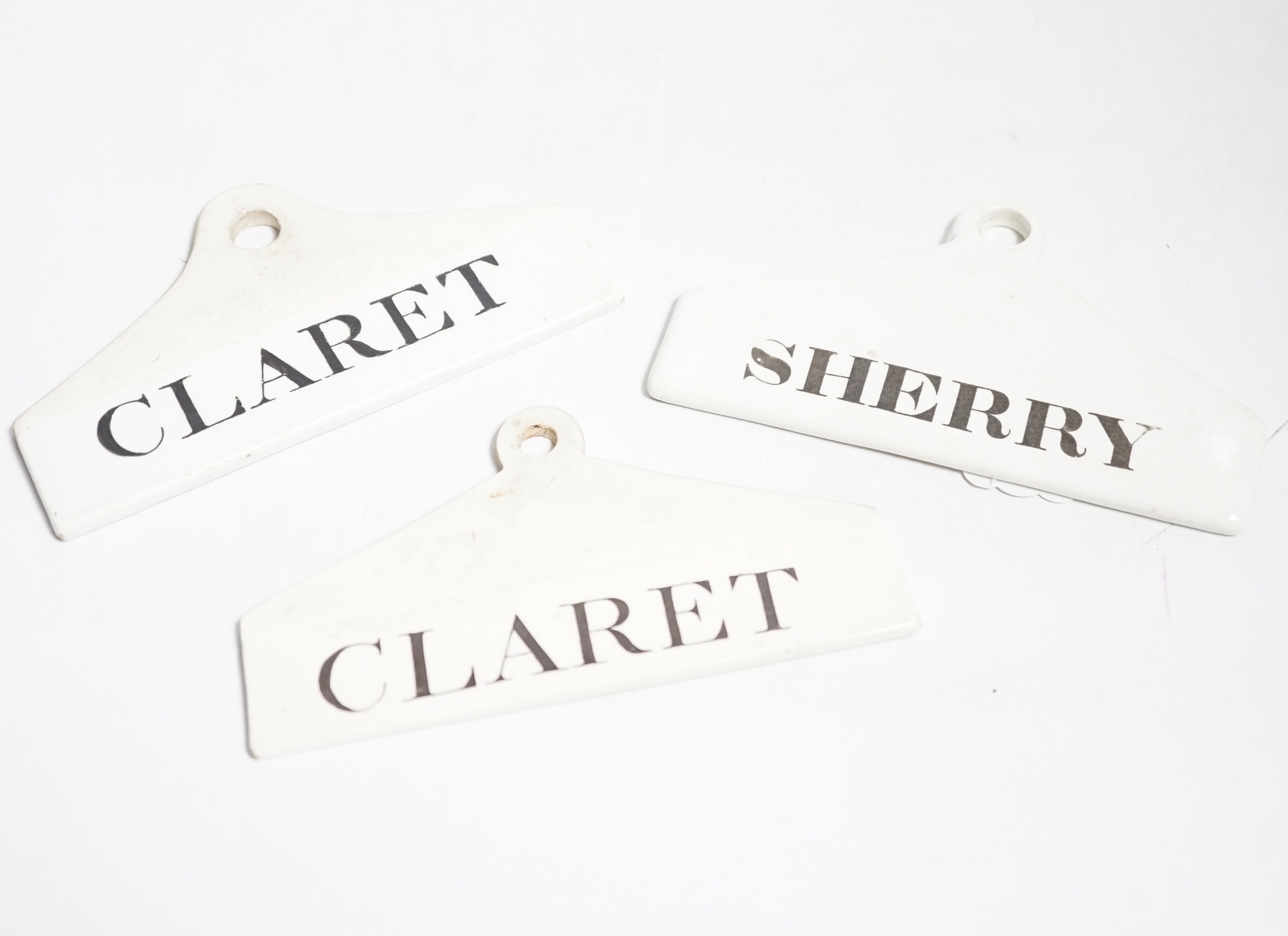 Three late 18th century creamware cellar labels, two claret stamped Wedgwood and one sherry, unmarked, 14 cms wide.